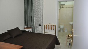 A bedroom with a bed, a bedside table, a mirror, and a view into the bathroom. - Chocolat Inn (Rome)