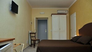 A bedroom with a bed, a chair, a wardrobe, a television, and an air conditioning unit. - Chocolat Inn (Rome)