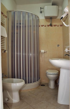 Un baño con cabina de ducha, inodoro, bidé y lavamanos.