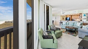 Un vaste espace de vie avec vue sur la plage, une cuisine dotée de meubles en bois et un balcon agrémenté d’une balustrade.
