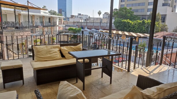 A balcony with wicker furniture, a table, and a view of the cityscape.