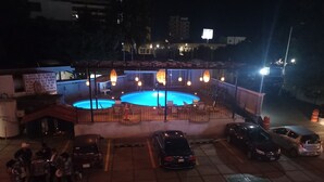A pool area with chairs and tables, surrounded by a fence and a sign in Spanish.