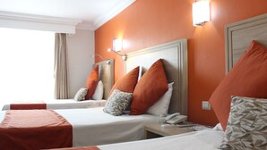 A hotel room with two beds, each with a headboard, a bedside table, and a lamp.