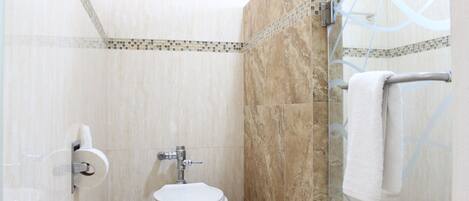 A bathroom with a toilet, a glass shower enclosure, and a towel rack.