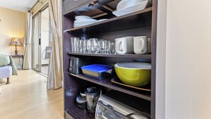 Una cocina con estantes que sostienen platos, vasos y una licuadora.