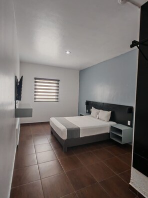 A modern bedroom with a bed, bedside tables, a window with blinds, and a wall-mounted shelf. - Alo Select Mazatlan (Mazatlán)