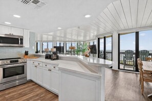 Een moderne keuken met witte kasten, roestvrijstalen apparatuur en een groot eiland.