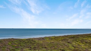 Eine Küstenlandschaft mit blauem Himmel und Blick aufs Meer.