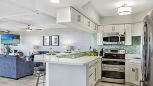 A modern kitchen with white cabinetry, a central island, stainless steel appliances, and a ceiling fan.
