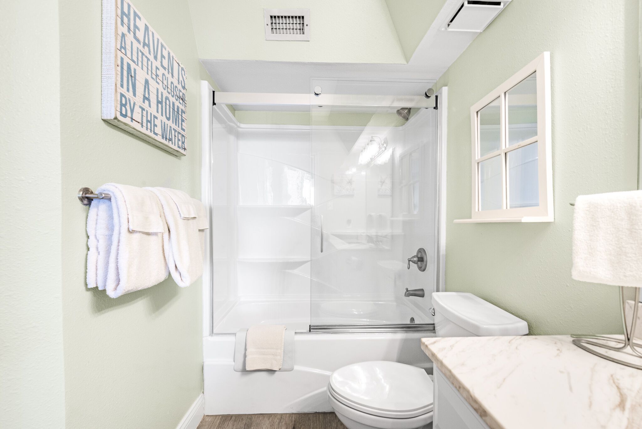 Un baño con ducha de vidrio, inodoro y lavamanos con encimera de mármol.
