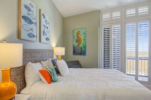 Habitación de hotel con una cama grande, dos lámparas de pared, un cabecero de mimbre y una pintura de un caballito de mar.