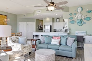 A modern living room with a teal sofa, a round coffee table, and a ceiling fan.