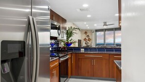 Eine moderne Küche mit Edelstahlgeräten, Holzschränken und einem großen Fenster mit Blick.