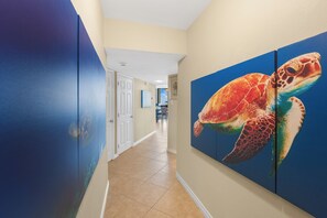 Un couloir avec un mur bleu, une porte et un grand tableau représentant une tortue de mer.
