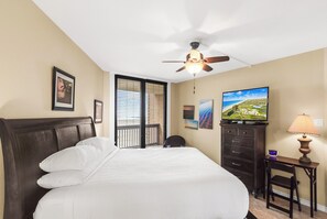 Une chambre d’hôtel équipée d’un lit, d’une télévision, d’un bureau avec une lampe et d’un ventilateur de plafond.