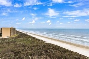 A beach with a sandy shore and a building in the background.