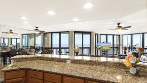 A spacious kitchen with a granite countertop, wooden cabinets, and a large island. - Sandpiper Condominiums 1104, Panoramic Gulf Views w/ direct access to Mustang Island/Port A beaches. (Port Aransas)