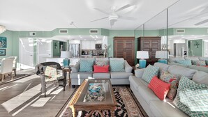 A spacious living room with a large sofa, a coffee table, and a dining area in the background.