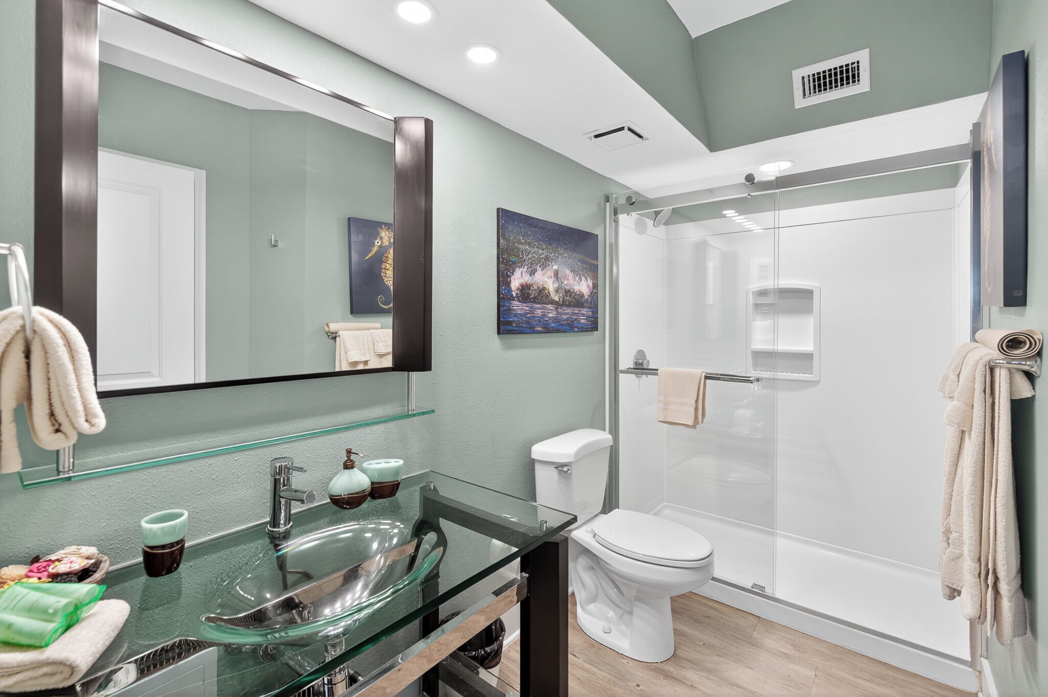 Une salle de bain moderne avec un lavabo en verre, des toilettes et une douche à parois de verre.