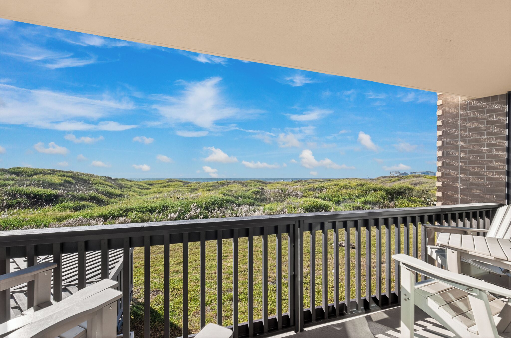 A balcony with a view of grassy hills and a clear sky.