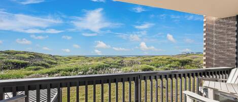 A balcony with a view of grassy hills and a clear sky.