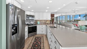 A modern kitchen with stainless steel appliances, white cabinetry, and a large island.