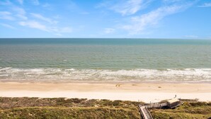 A beach with a wooden boardwalk leading to a building. - Sandpiper Condominiums 1104L, Panoramic Gulf View w/ direct access to Mustang Island/Port A beaches. (Port Aransas)
