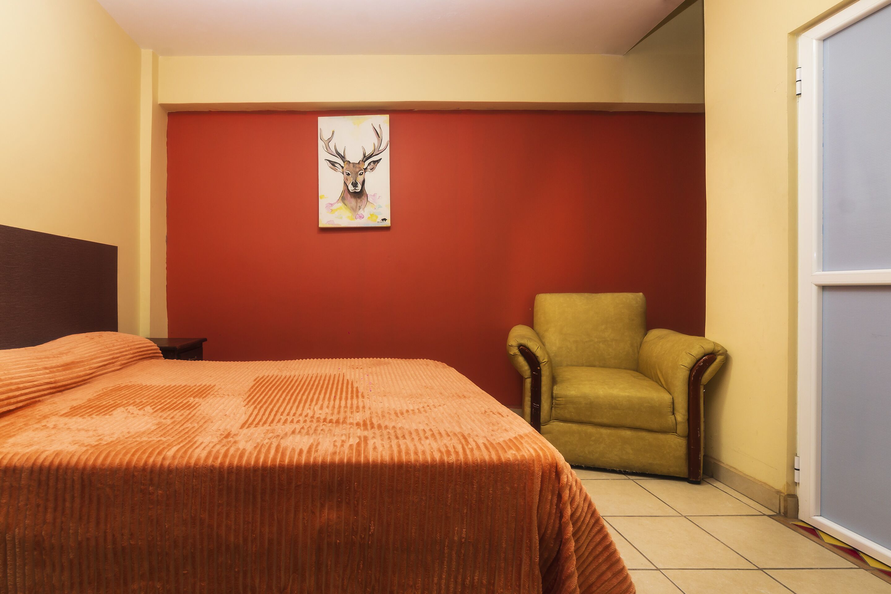 Une pièce avec un lit, une chaise et un tableau au mur.
