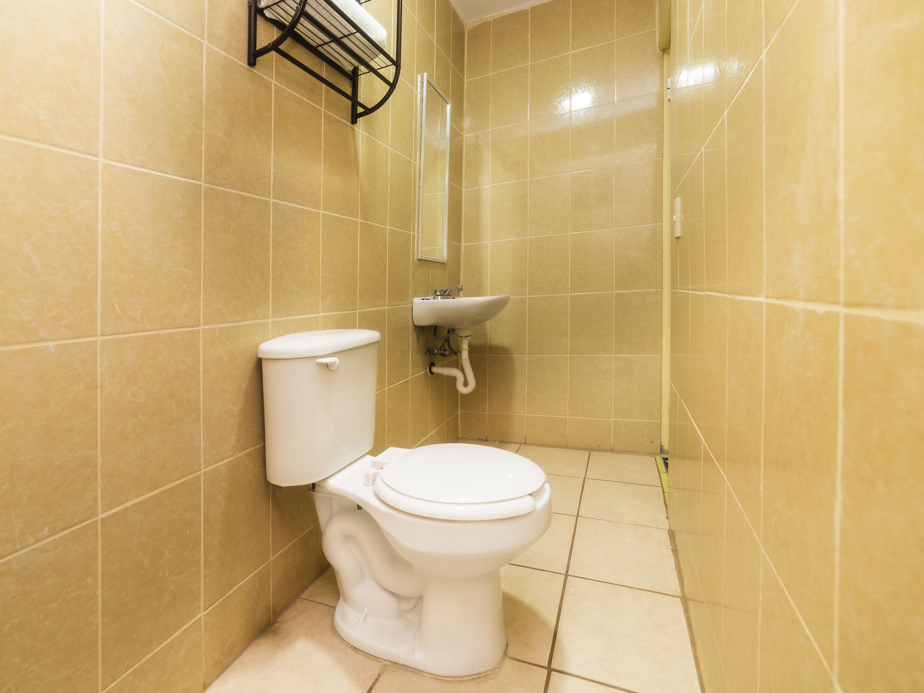 Une petite salle de bain avec des toilettes, un lavabo et des murs carrelés.