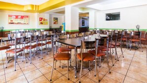 Un amplio comedor con varias mesas y sillas, un tablero de menú y una máquina expendedora.