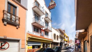 Una calle con edificios, incluyendo un hotel con un letrero que dice 'Follos Asados' y un restaurante llamado 'Pollo de Feliz'.