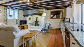 Un salon chaleureux avec un canapé, une petite table en bois, un téléviseur et une cheminée en pierre.