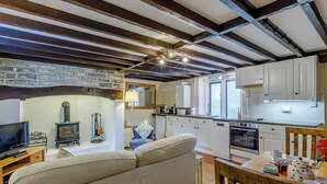 Un salon confortable avec un canapé, une télévision, une cheminée et un coin repas comprenant une table et des chaises.