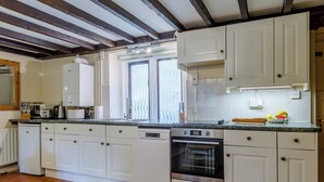 Une cuisine avec des meubles blancs, un four encastré, un lave-vaisselle et une fenêtre donnant sur un beau paysage.