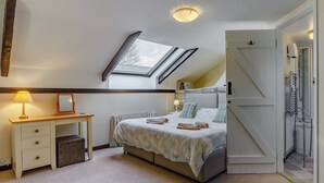 Une chambre avec un puits de lumière, une table de chevet avec une lampe, un lit avec des oreillers et un radiateur.