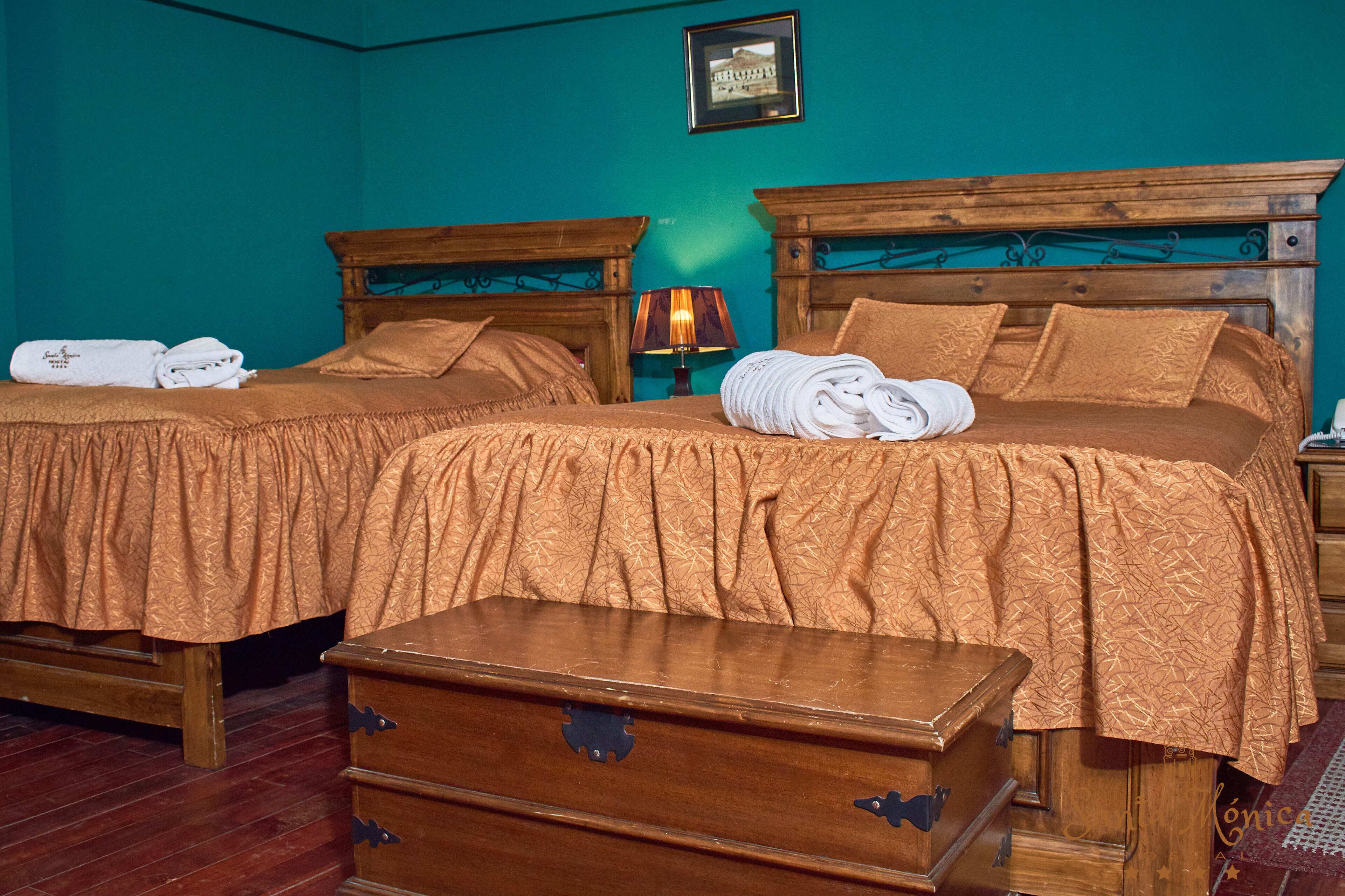 Une chambre double avec deux lits, une commode en bois et une lampe.