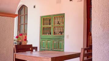 Un comedor con una mesa y sillas de madera, un armario verde con botellas y una araña.
