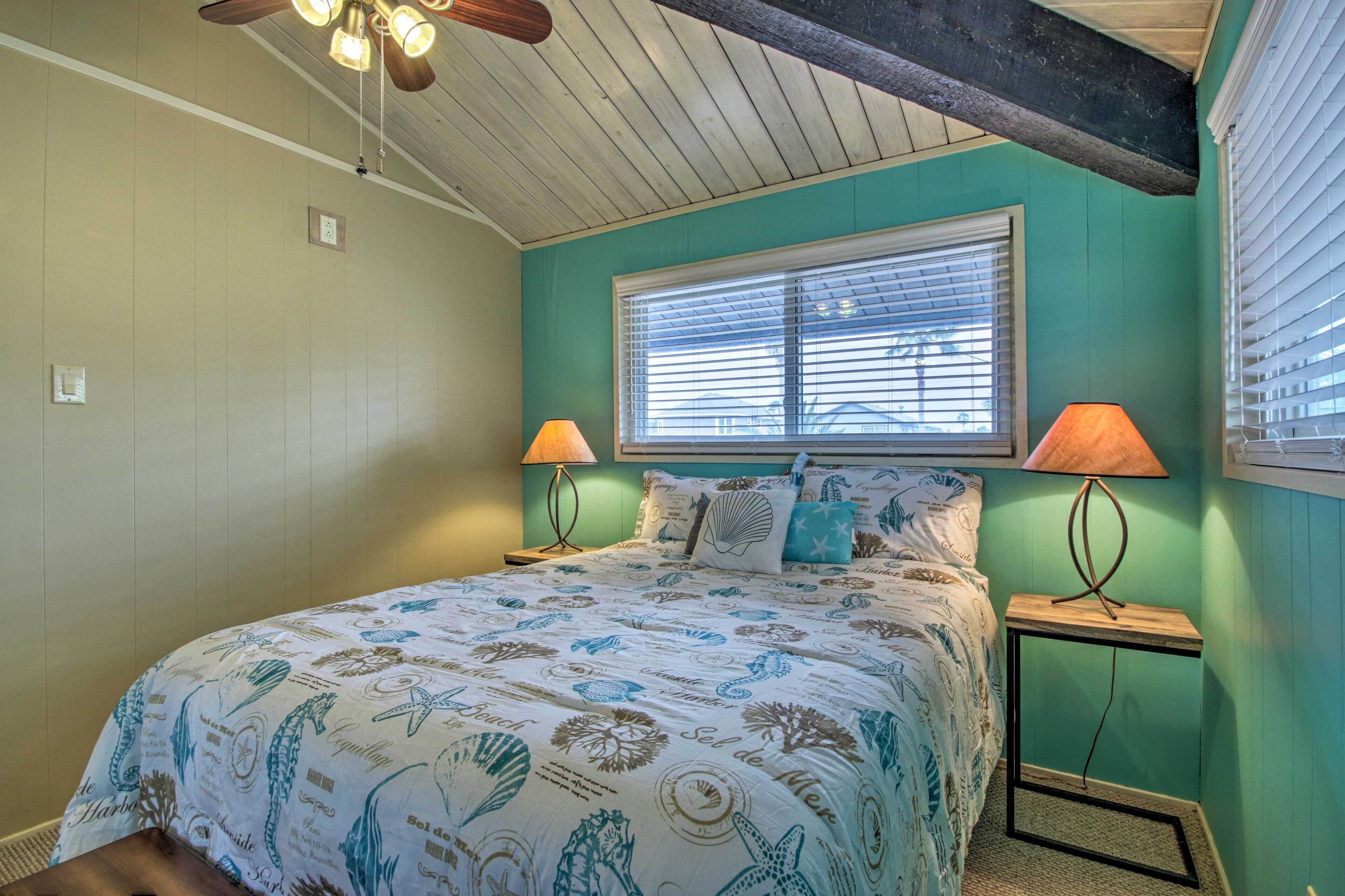 A bedroom with a bed, two bedside lamps, a window, and a ceiling fan.