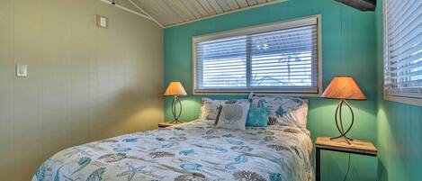 A bedroom with a bed, two bedside lamps, a window, and a ceiling fan.