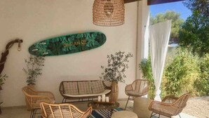 Een gezellig buiten zitgedeelte met rieten meubels, een skateboard en decoratieve planten.