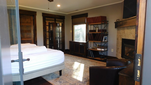 Un dormitorio con cama, chimenea, estantería y ventilador de techo.