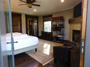 A bedroom with a bed, a fireplace, a bookshelf, and a ceiling fan.