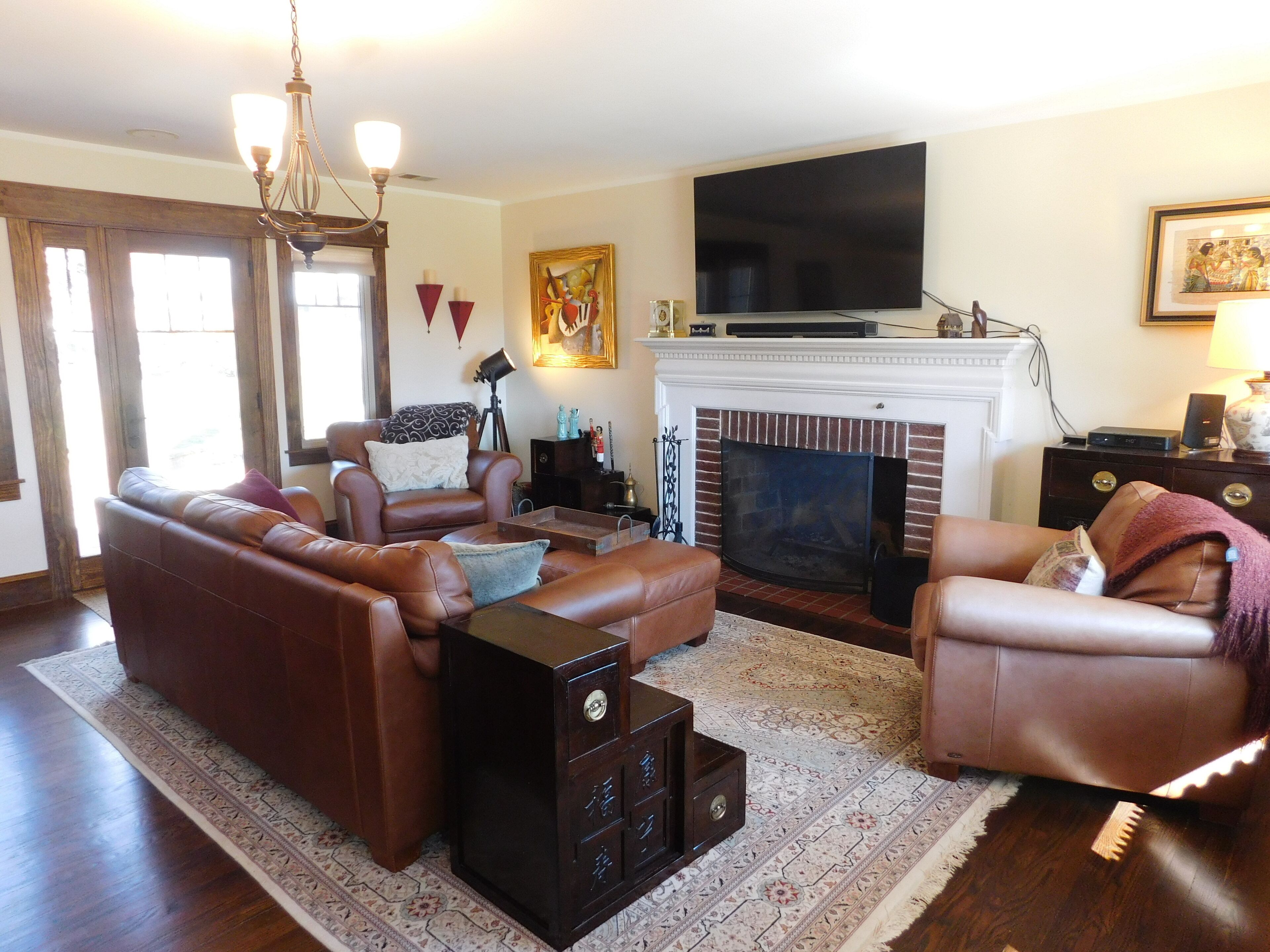 A living room with a fireplace, leather sofas, a television, and a patterned rug.