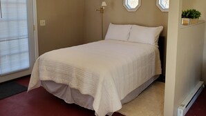 A bedroom with a bed, a window with blinds, a floor lamp, and a radiator.