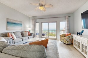 Relax in this stylish living room with a sofa, coffee table, and armchair, plus a balcony with ocean views.