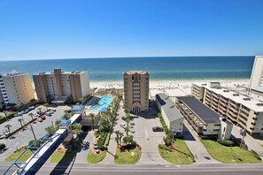 A beachfront hotel with multiple buildings, a swimming pool, and a parking area.