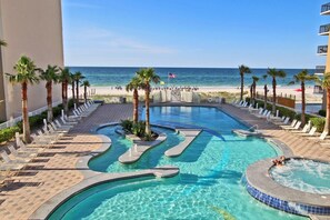A pool area with a view of the beach, palm trees, and lounge chairs. - Crystal Tower 609 (Gulf Shores)
