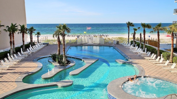 A pool area with multiple swimming sections, a hot tub, and a view of the beach. - Crystal Tower 1907 (Gulf Shores)