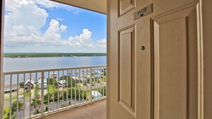 Un balcon donnant sur un lac, un parking et un immeuble dont la porte porte le numéro 1608.