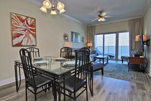A dining area with a glass table, black chairs, and a ceiling fan.